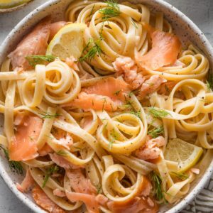 Bowl full of smoked salmon pasta garnished with fresh parsley and dill.