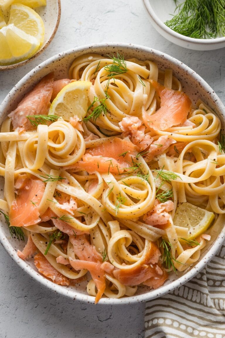 Bowl full of smoked salmon pasta garnished with fresh parsley and dill.