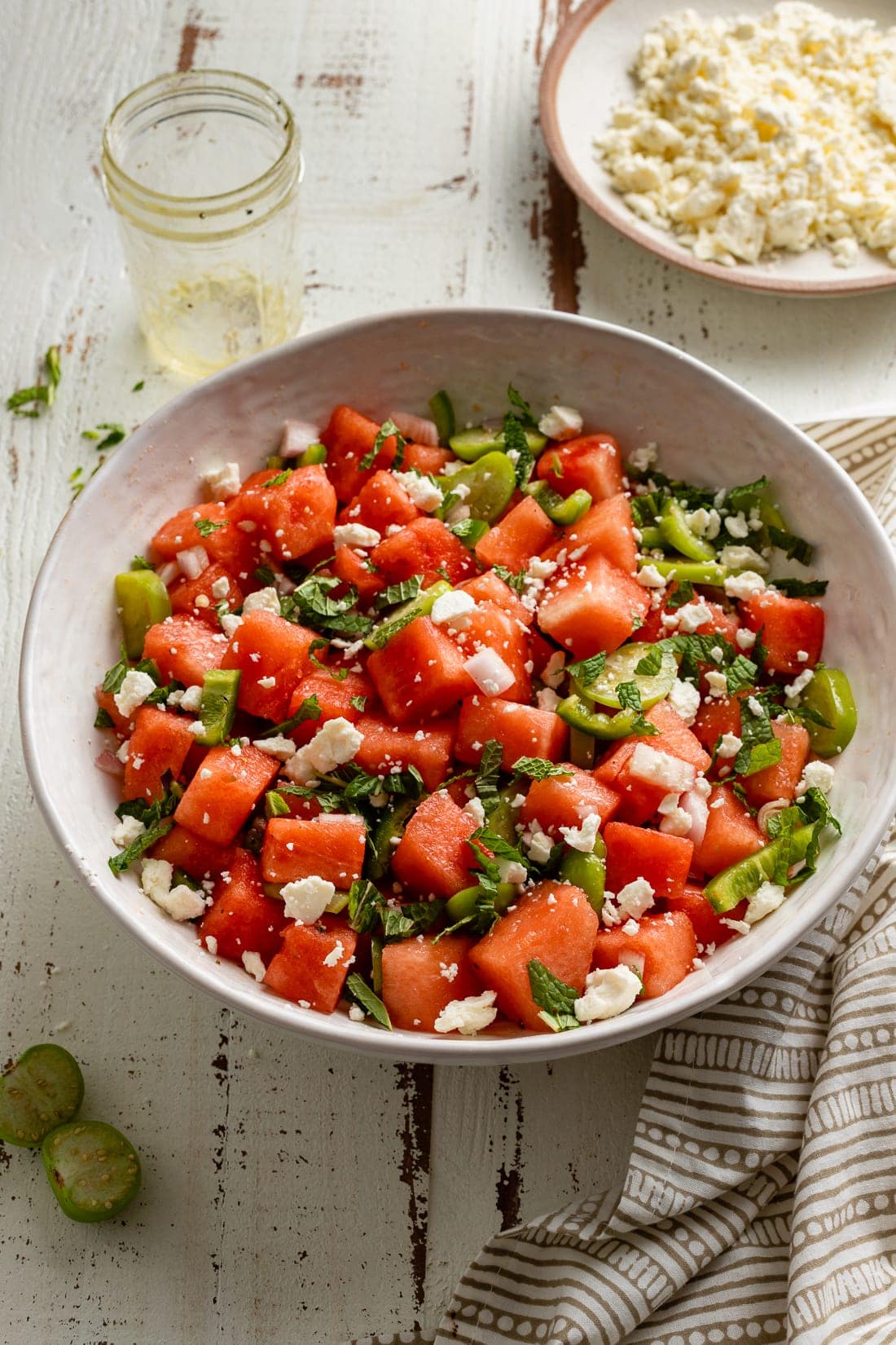 A large serving bowl of fresh watermelon salad with tomatillos, jalapenos, and lime dressing.