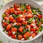 A large serving bowl of fresh watermelon salad with tomatillos, jalapenos, and lime dressing.