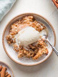 Close up of an old fashioned apple crisp served with a scoop of vanilla ice cream.