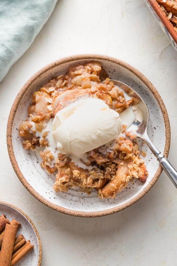Close up of an old fashioned apple crisp served with a scoop of vanilla ice cream.