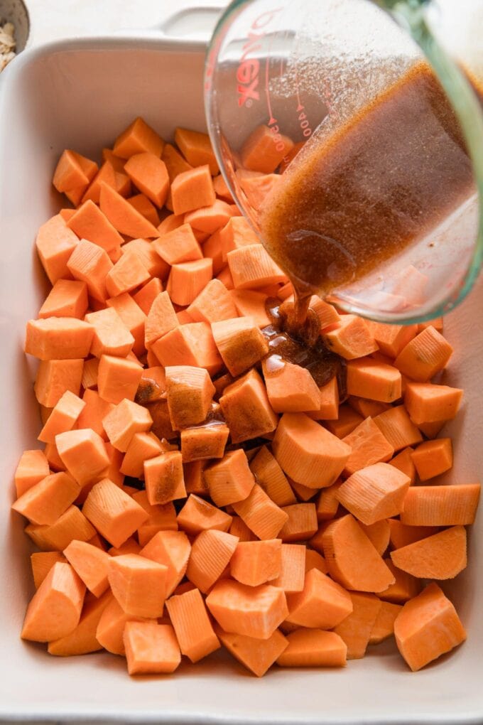 Butter-honey mixture being poured over cubed sweet potatoes.