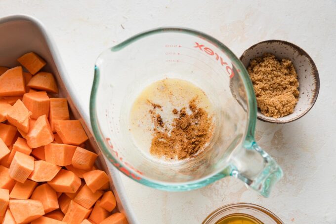 Melted butter in a glass liquid measuring cup with ground cinnamon, honey, and salt sprinkled in.