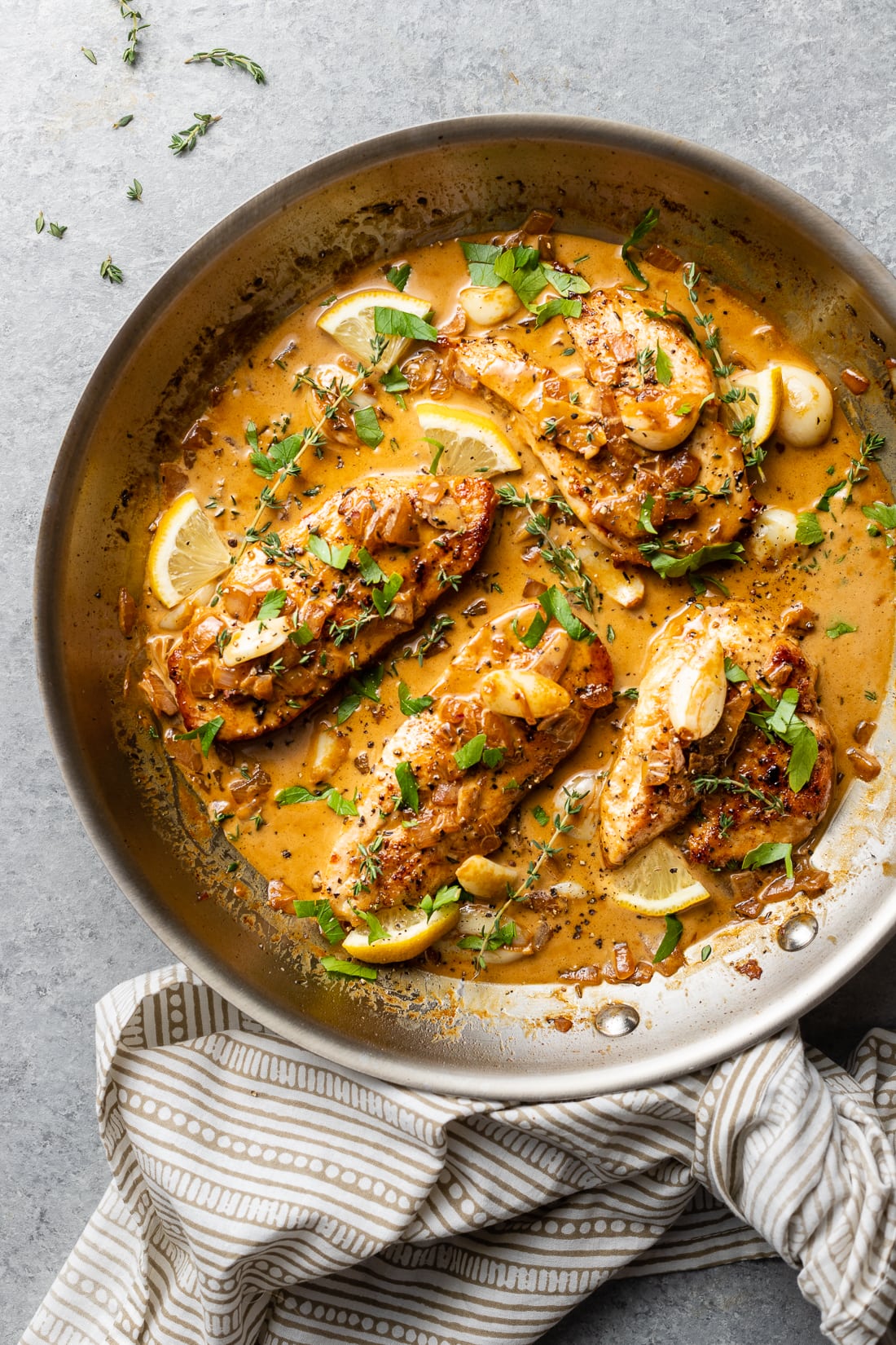 Creamy garlic chicken in a skillet with fresh herbs.