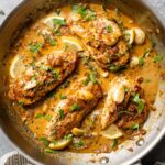 Creamy garlic chicken in a skillet with fresh herbs.