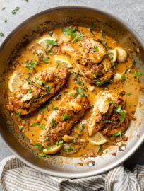 Creamy garlic chicken in a skillet with fresh herbs.