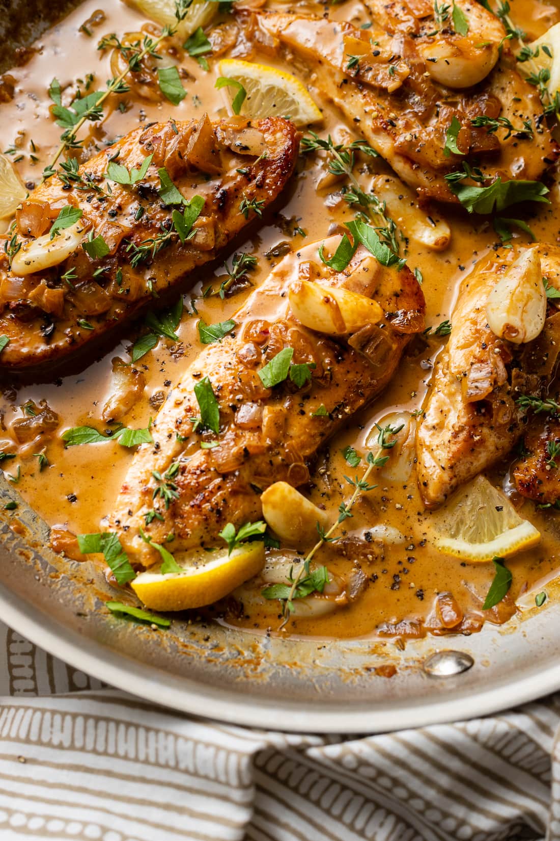 Close-up of creamy garlic chicken with herbs and lemon.