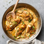 Creamy garlic chicken in a skillet with fresh herbs.