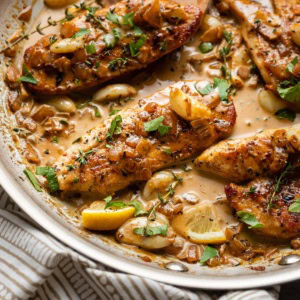 A spoon pouring sauce over creamy garlic chicken.