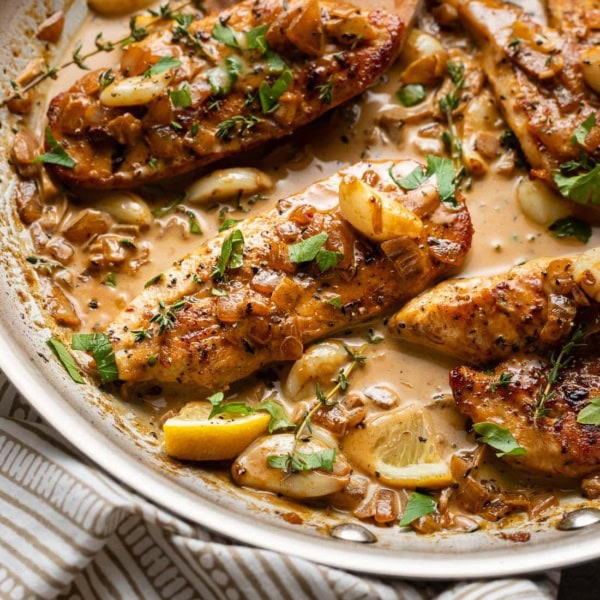 A spoon pouring sauce over creamy garlic chicken.