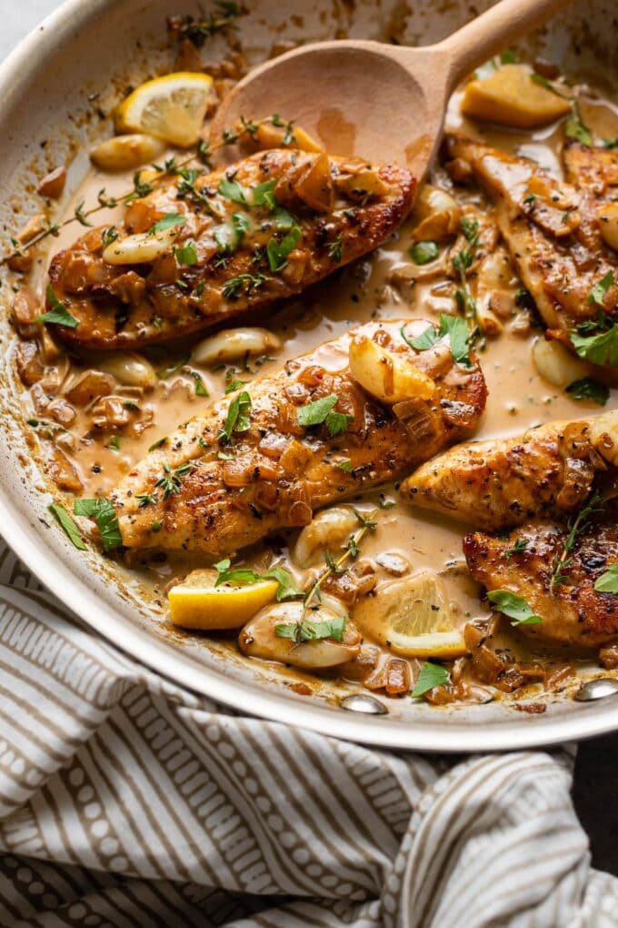A spoon pouring sauce over creamy garlic chicken.