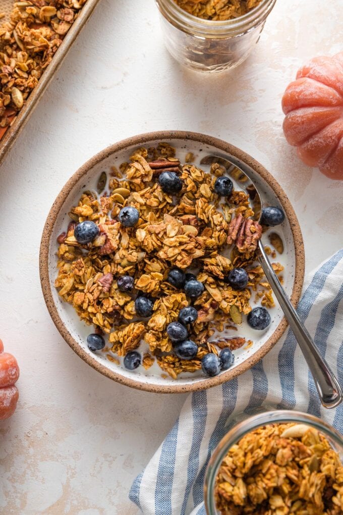 Small bowl filled with almond milk, pumpkin granola, and blueberries.