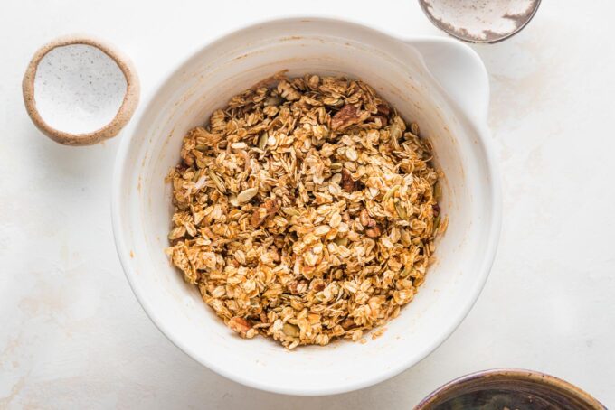 Uncooked granola mixture combined in a large white bowl.