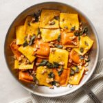 Skillet filled with pumpkin ravioli, sage brown butter sauce, crisped sage leaves, and walnuts.