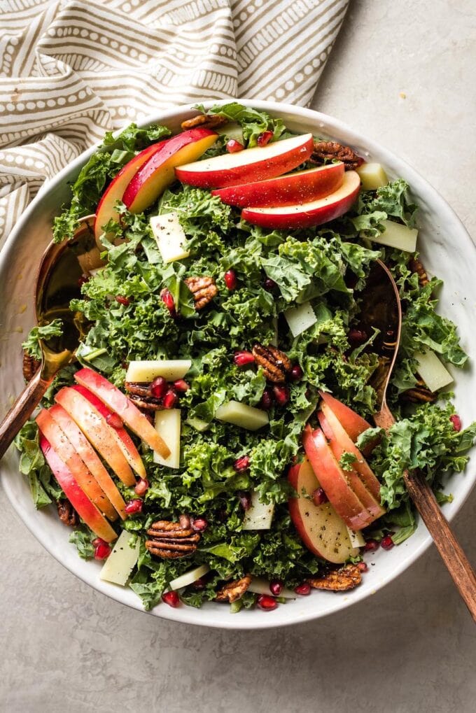 Large white ceramic bowl filled with a kale apple salad.