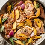 A spoon about to serve helpings of pork chops with apples and onions.