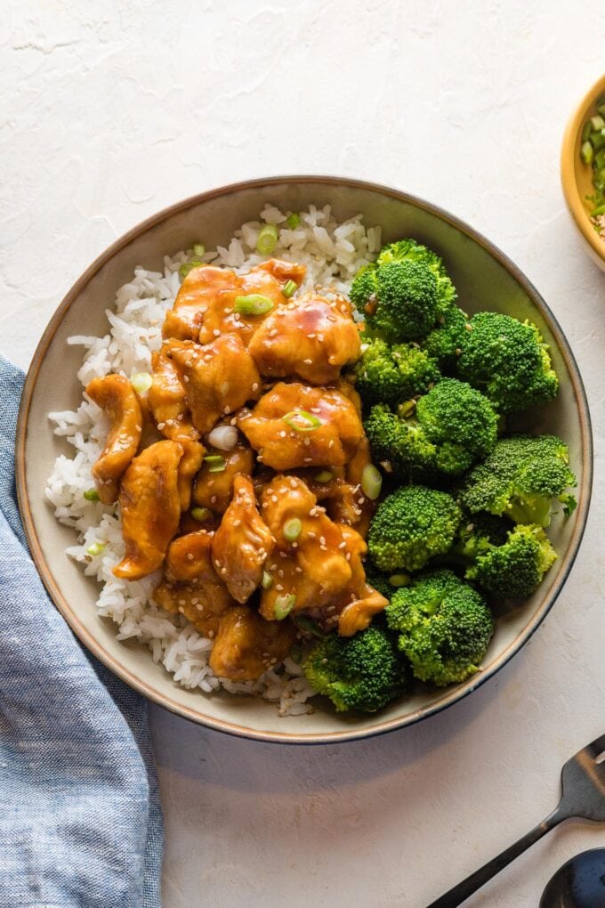 Bowl of homemade bourbon chicken served with broccoli and rice.