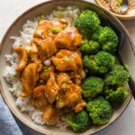 Bowl of homemade bourbon chicken served with broccoli and rice.