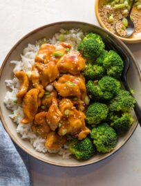 Bowl of homemade bourbon chicken served with broccoli and rice.