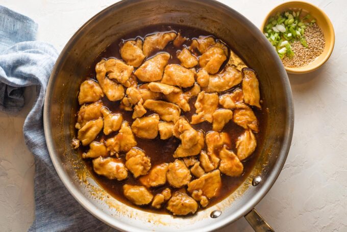 Skillet with cooked chicken and bourbon sauce.