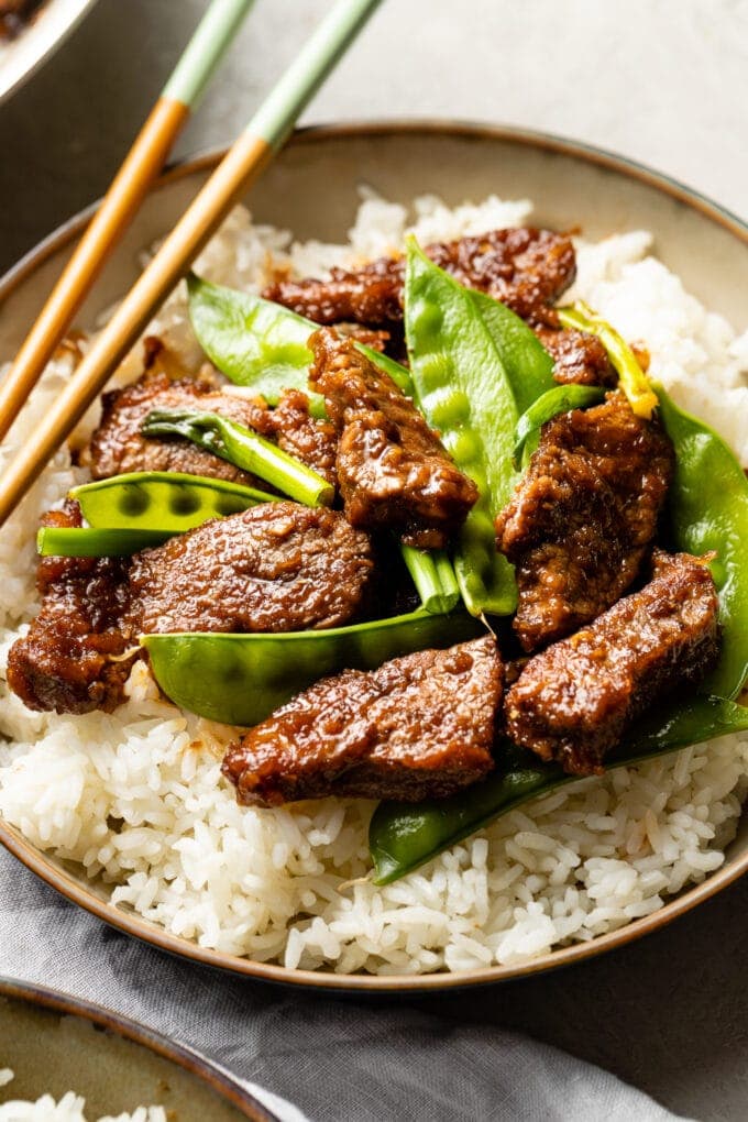 Close up of Mongolian beef with snow peas served over white rice.