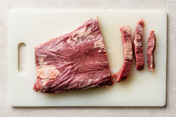 Flank steak on a cutting board, showing how to cut against the grain.