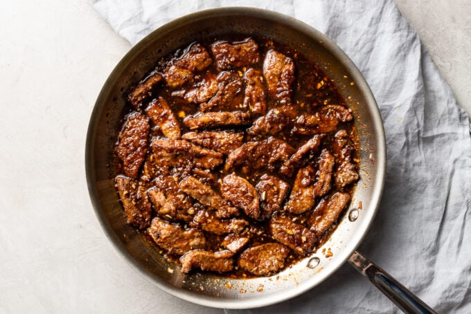 Steak pieces returned to the skillet with the sauce.