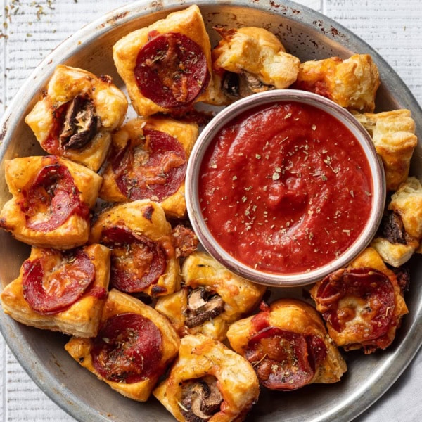 Puff pastry pizza bites with pepperoni and mushrooms served with dipping sauce.