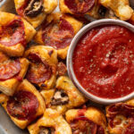 Puff pastry pizza bites with pepperoni and mushrooms served with dipping sauce.