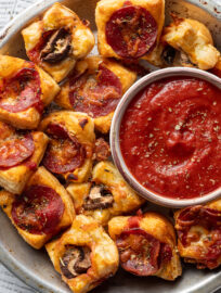 Puff pastry pizza bites with pepperoni and mushrooms served with dipping sauce.