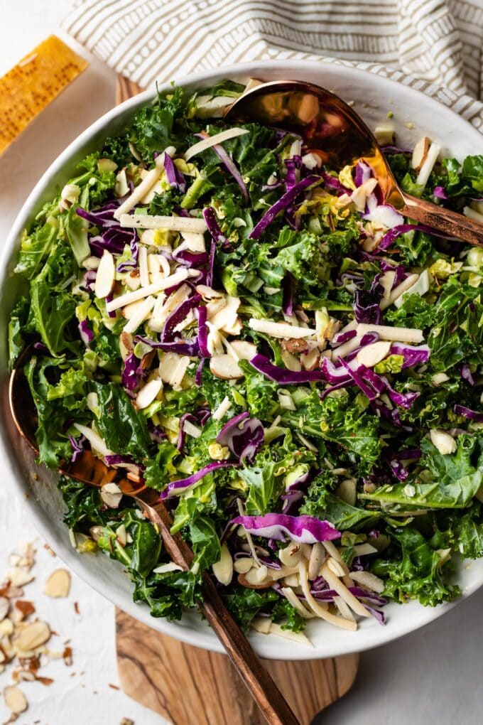 Salad with kale, Brussels sprouts, and red cabbage served in a white bowl.