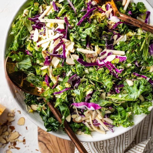 Healthy and easy kale Brussels sprout salad with red cabbage, sliced almonds, and lemon Parmesan dressing..
