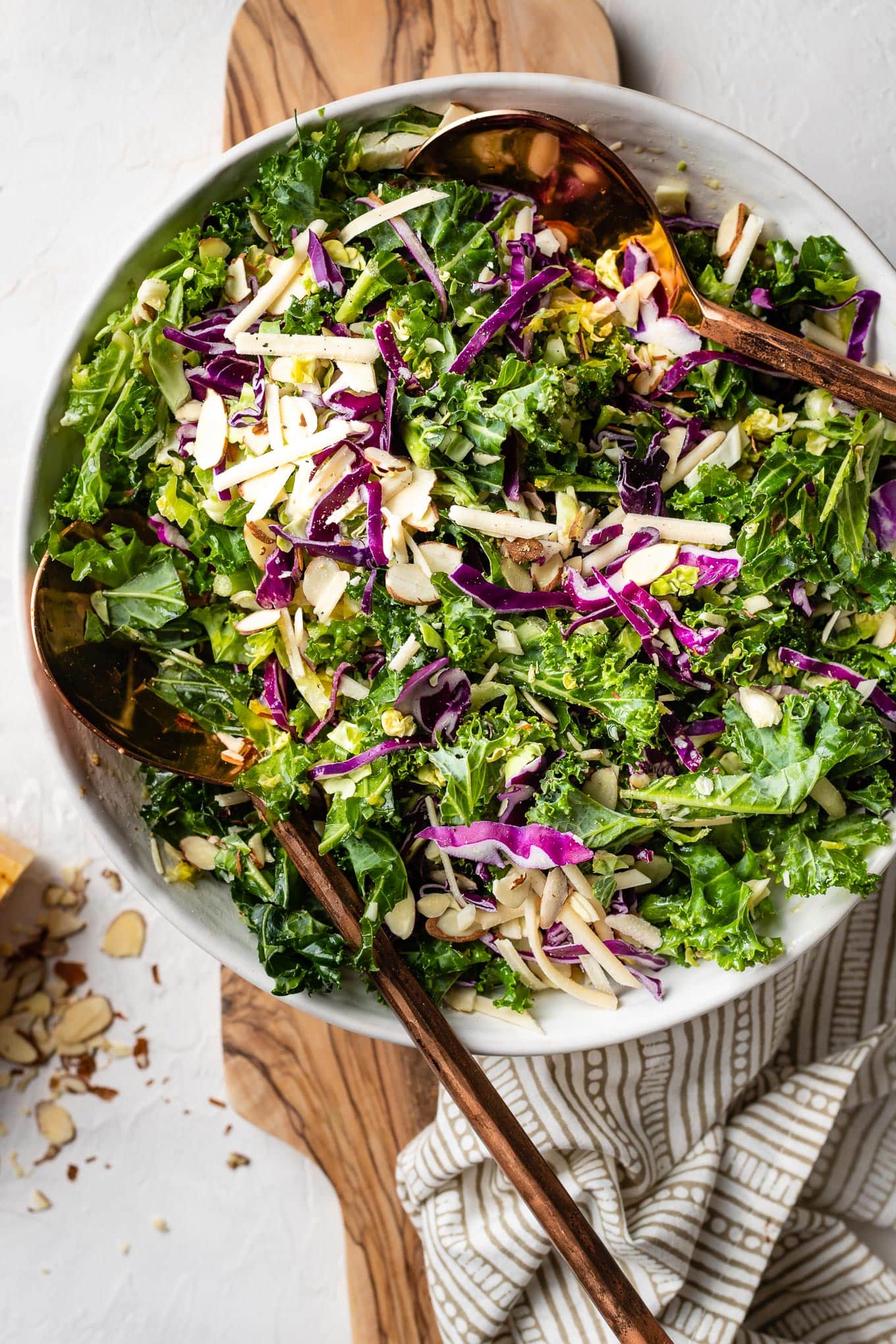 Healthy and easy kale Brussels sprout salad with red cabbage, sliced almonds, and lemon Parmesan dressing..