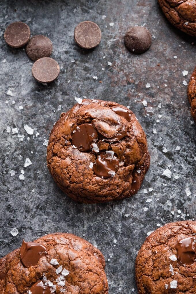 Close up of a dark chocolate cookie with chocolate chunks and sea salt sprinkled on top.