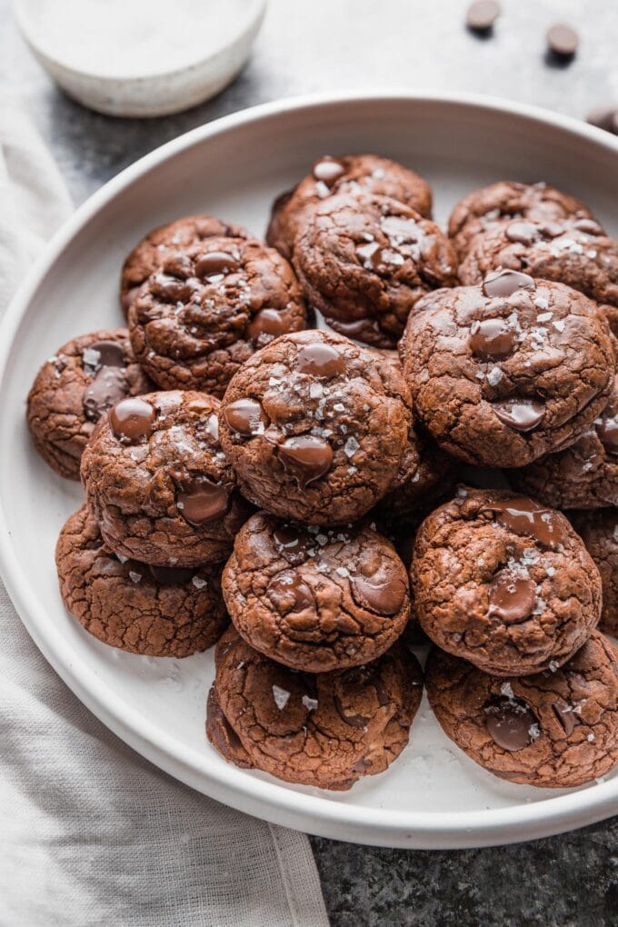 Large white plate full of dark chocolate cookies.