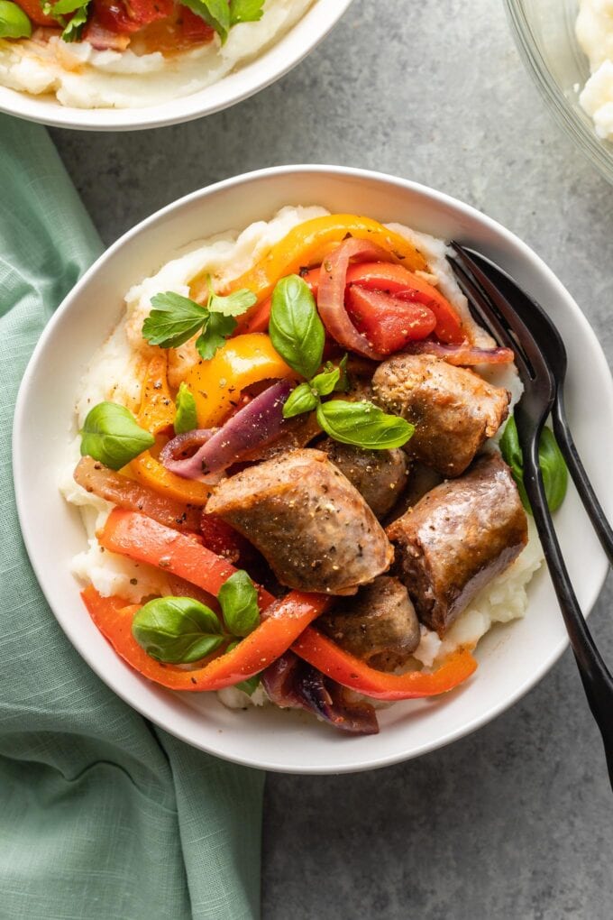 Bowls of Italian sausages, peppers, and onions served with creamy mashed potatoes.