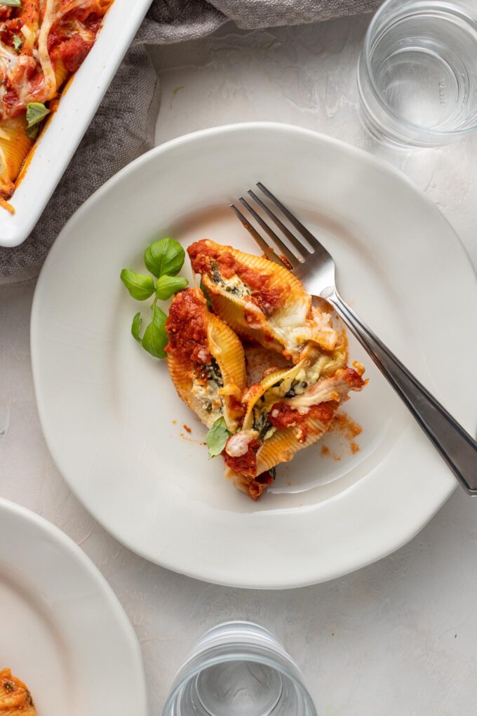 Small white plates with individual servings of spinach and ricotta stuffed shells.