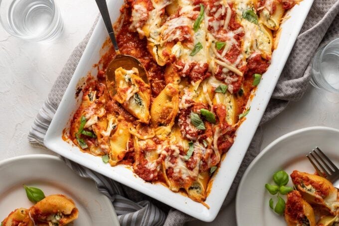 A large baking dish filled with baked stuffed shells filled with ricotta and spinach.