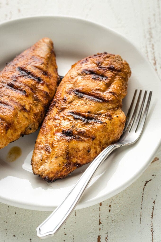 Juicy grilled chicken breasts on a white plate.