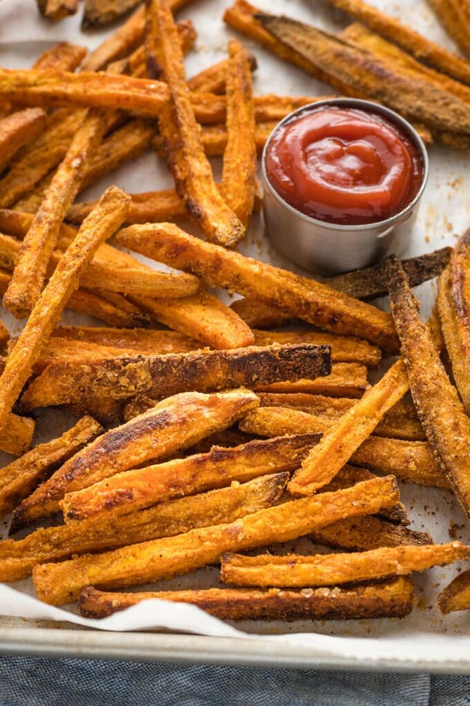 Sweet potato fries on a sheet pan with ketchup.