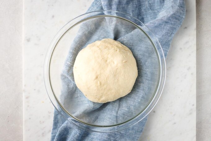 Bread dough just after kneading, halfway filling a clear prep bowl.