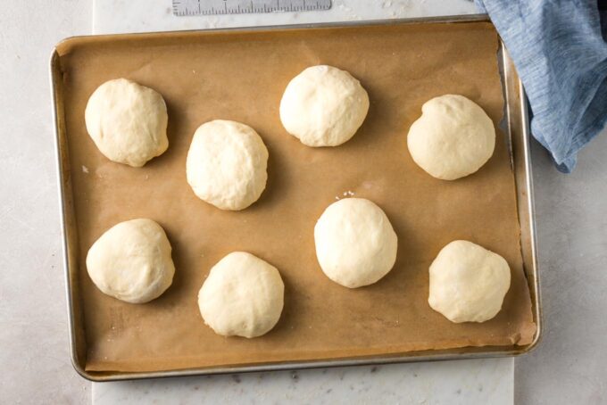Shaped rolls on a parchment-lined baking sheet.