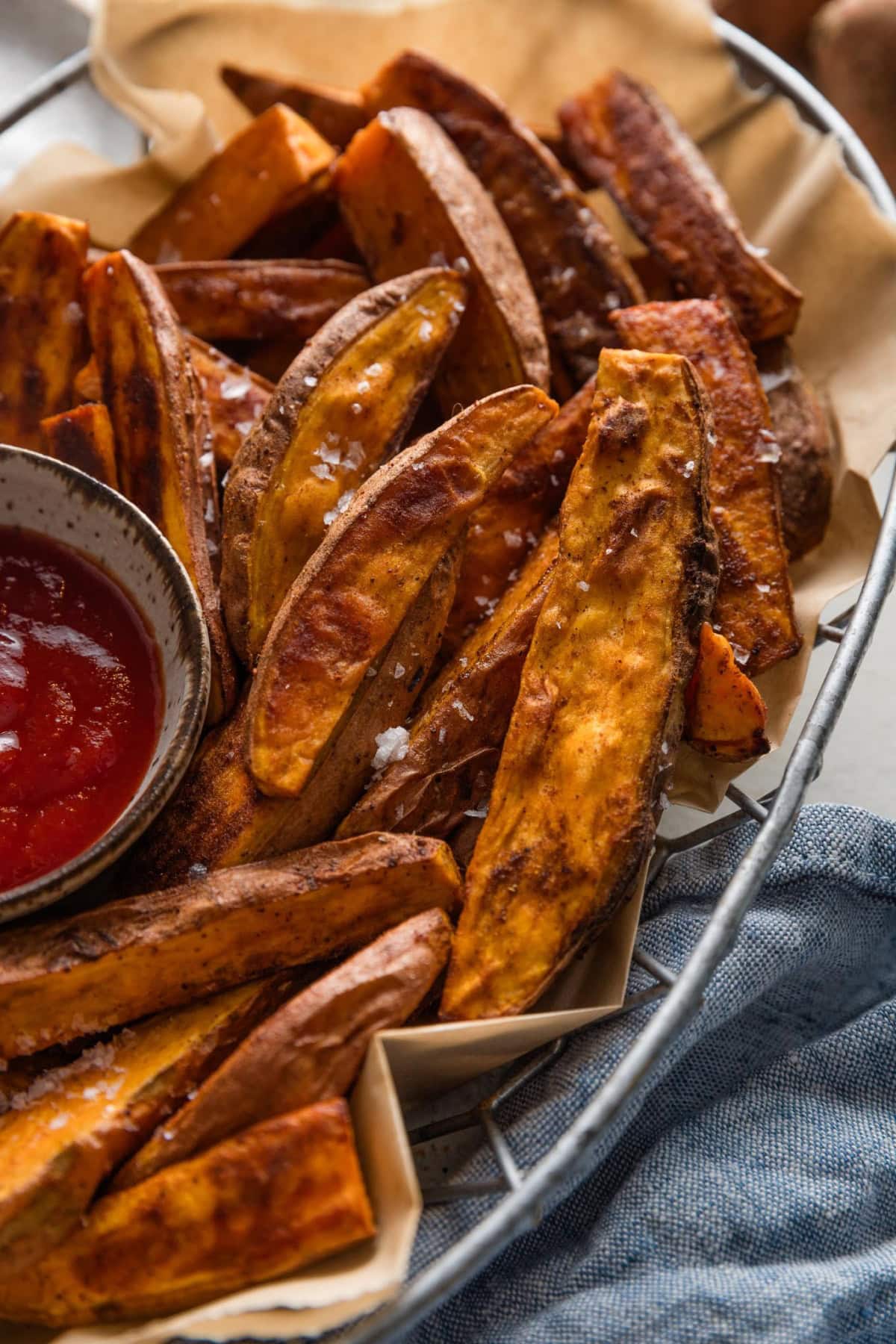 Close up of homemade sweet potato wedges in a metal basket.