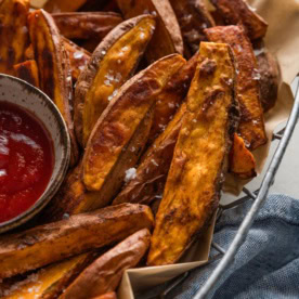 Close up of homemade sweet potato wedges in a metal basket.
