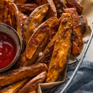 Close up of homemade sweet potato wedges in a metal basket.