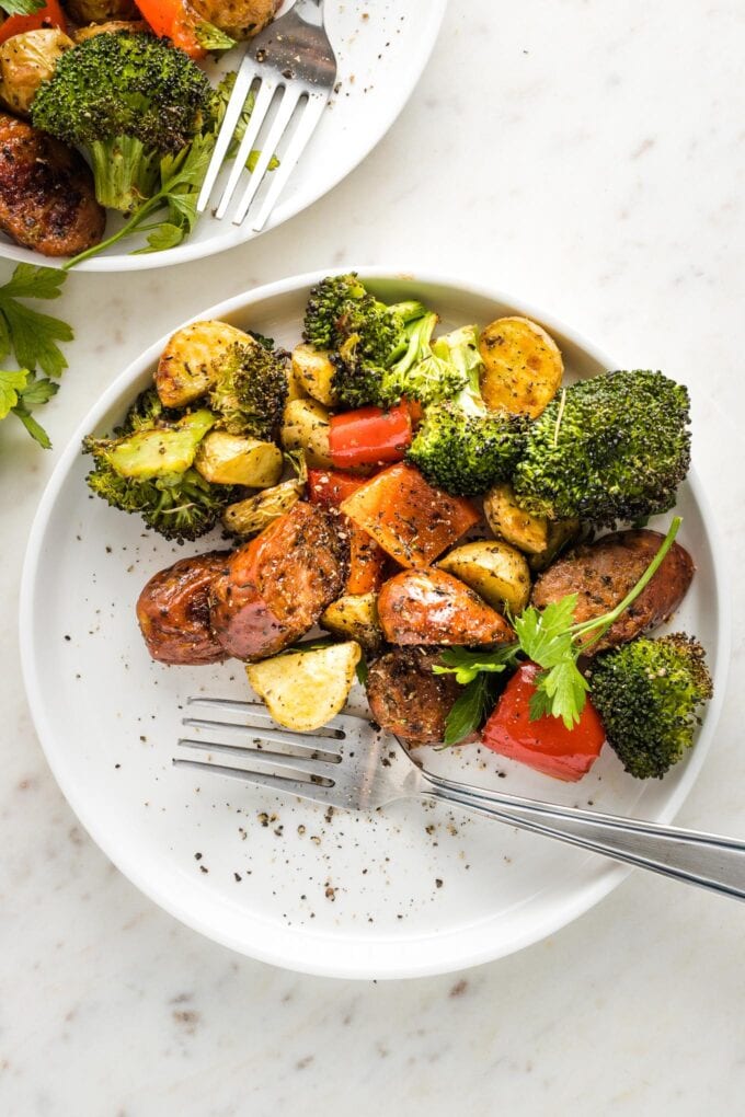 Small white plate with a serving of sausage, broccoli, pepper, and potatoes.