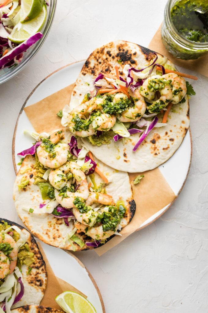 Overhead image of two shrimp tacos served with green chile adobo sauce.