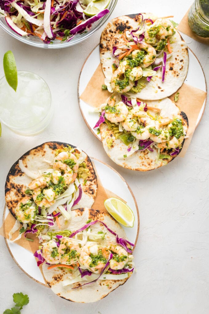 Shrimp tacos served with adobo verde, slaw, and avocado.