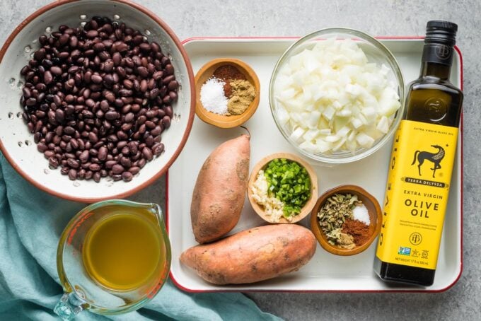 Black beans, broth, spices, sweet potatoes, onion, jalapeno, garlic, and olive oil in prep bowls.